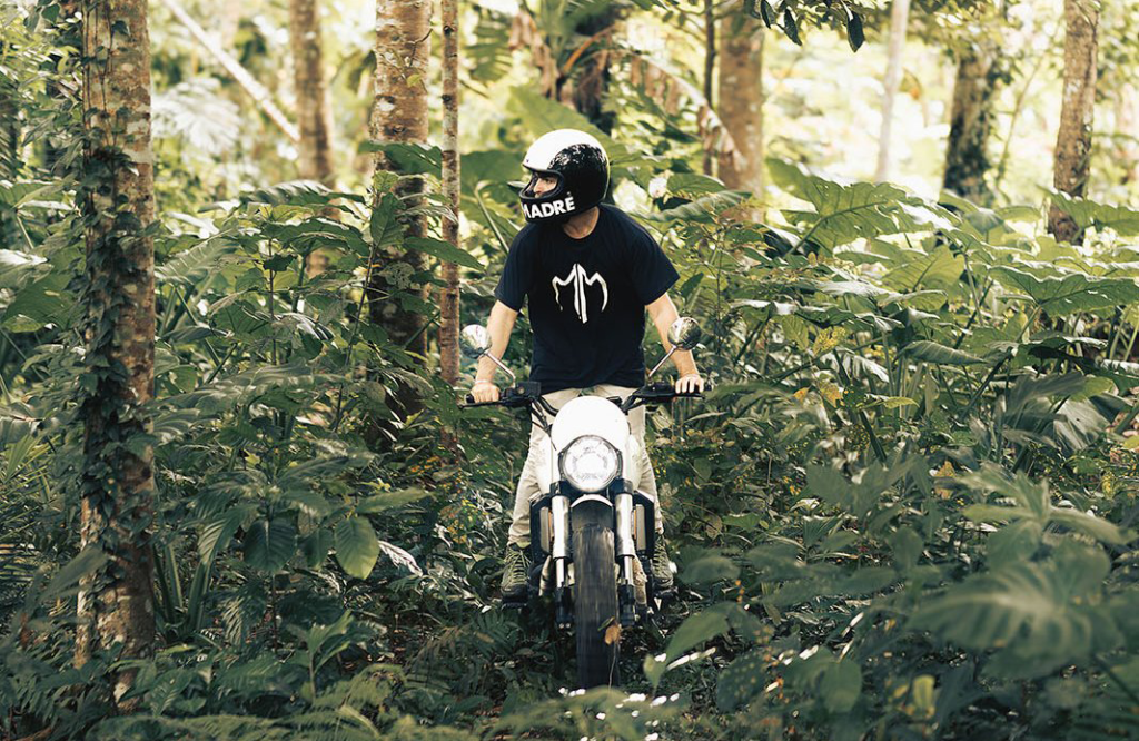 Noel Forseas, high-quality sports photographer Lombok. A man riding a motorbike trough the middle of a forest.